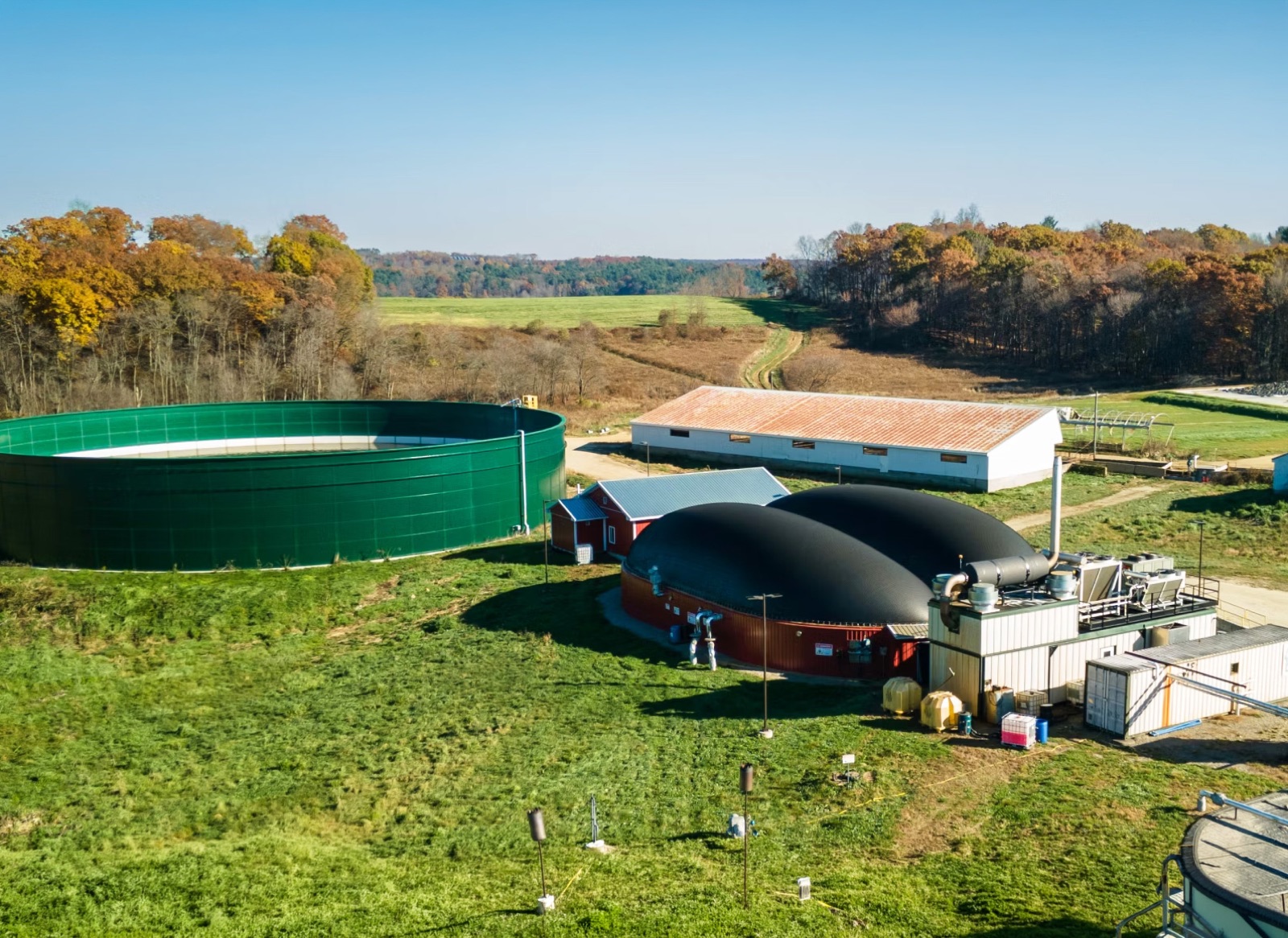Aerial view of a dairy farm anaerobic digester with green slurry tank, providing residual heat for FlowDrya forage drying