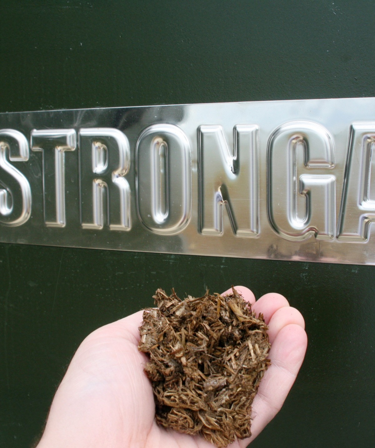 Dried digestate fibre material held in hand next to Stronga FlowDrya equipment