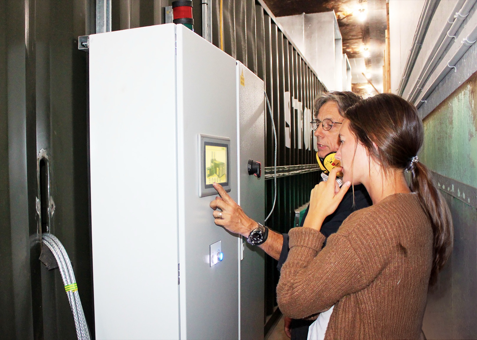 Operators reviewing FlowDrya DryStation control panel on hemp dryer in Oregon, USA