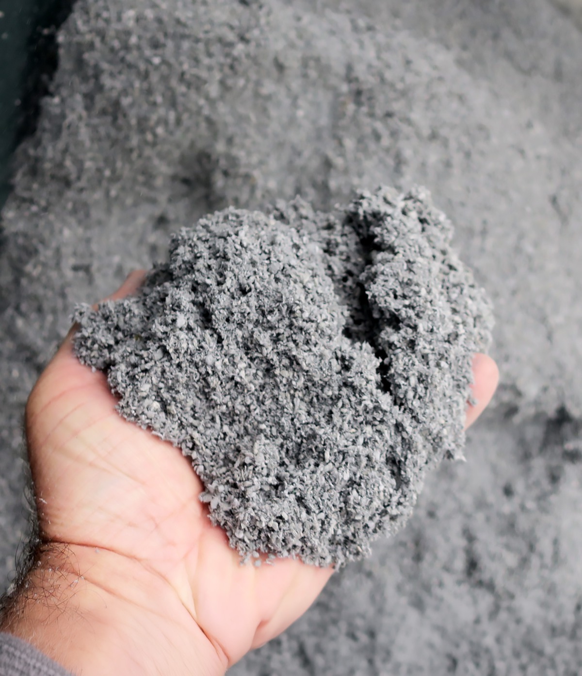 Hand holding dried paper crumb showing fine fibrous texture suitable for soil amendment